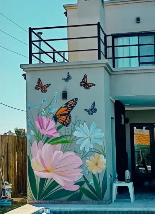 La misma pared del tanque, pintada de verde agua con flores rosadas y celestes y mariposas monarca.