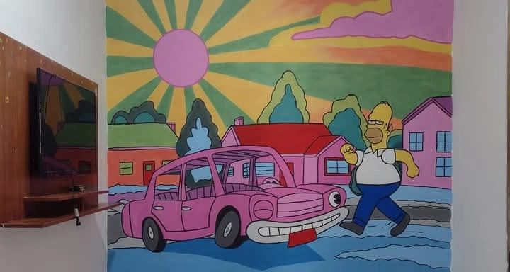 Mural de temática Simpson con una casa, un auto rosa y un sol de rayos, sobre pared de living.